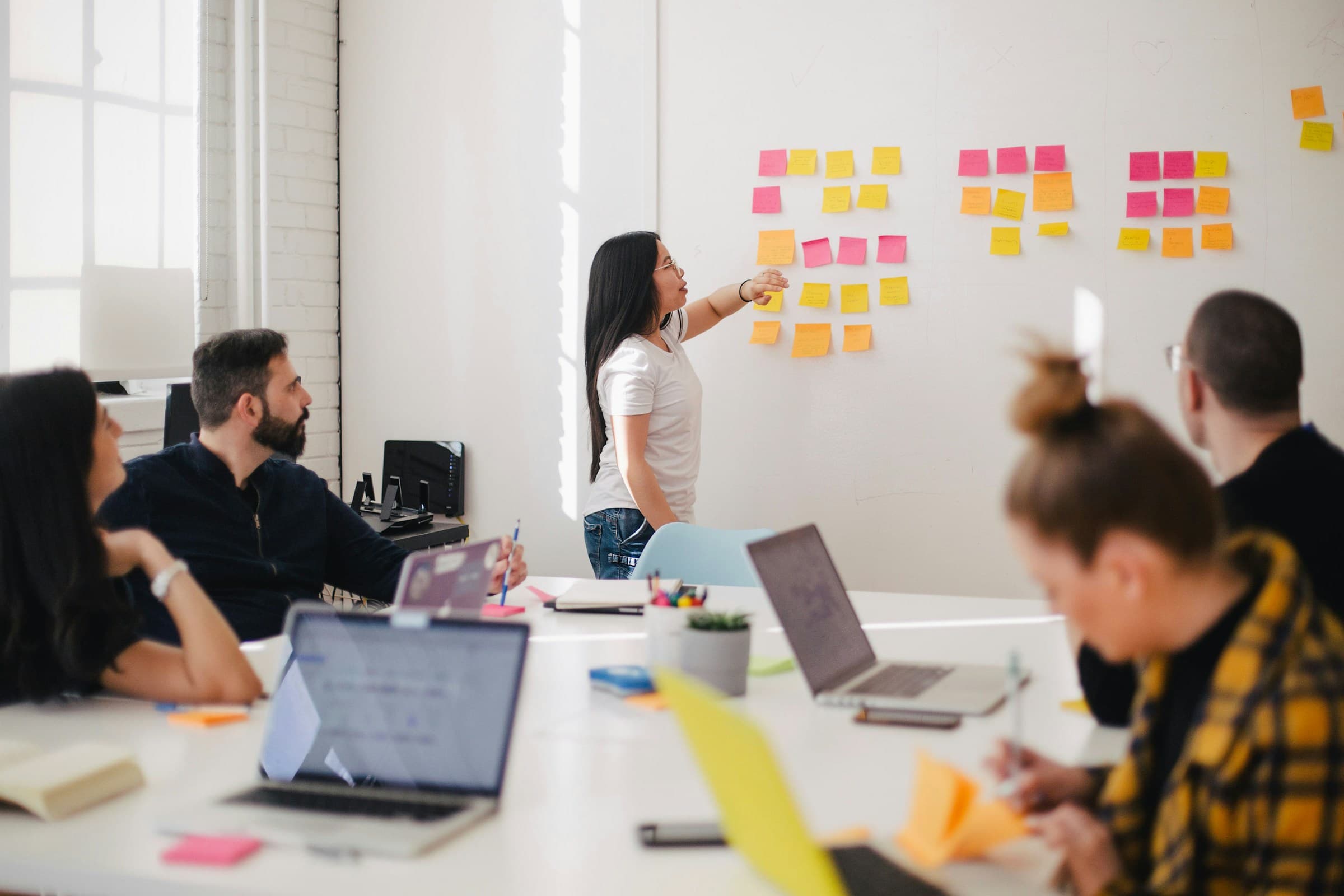 Operators planning execution at a workshop wall covered in sticky-note action items